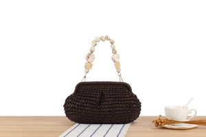 Detail of hand-woven dark brown handbag featuring unique marble texture resin bead handle