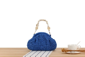 Detail of blue woven handbag featuring beaded marble handles and gold buckle accents