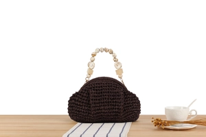Detail of dark brown crochet handbag with unique beaded marble and amber handles