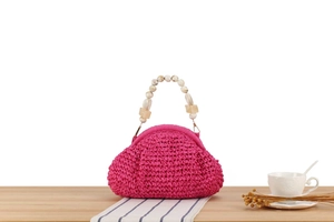 Detail of fuchsia woven straw bag with marble bead handles and golden metal buckle