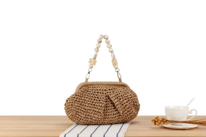 Detail of straw woven bag featuring marble texture bead handle and vintage metal clasp