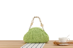 Detail of light green woven handbag with marble resin beads and amber handle design