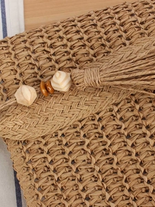 Handwoven straw bag with tassel and wood beads for a stylish seaside vacation look
