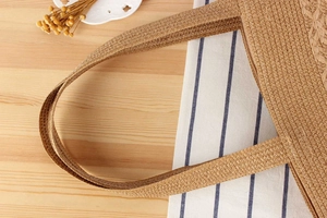 Close-up of woven straw tote bag featuring detailed craftsmanship and durable wide shoulder strap