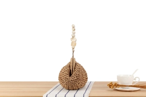 Close-up of a woven handbag with marble beaded handle on a striped tablecloth