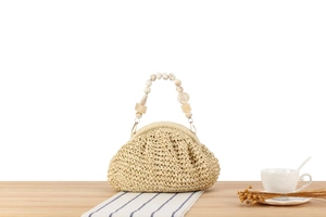 Detailed shot of beige woven bag with elegant marble resin bead handle and texture