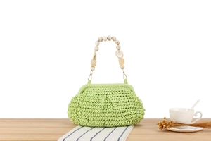 Detail of lime green woven handbag featuring unique marble-patterned beaded handle strap