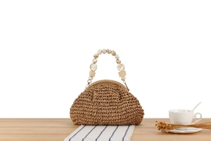 Detail of straw woven handbag featuring marble resin bead handles and natural fiber texture