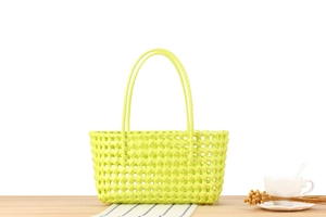 Detailed view of neon green hollow woven basket bag with round handles on a table