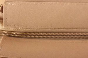 Macro shot showing reinforced stitching and durable nylon zipper on a khaki woven bag