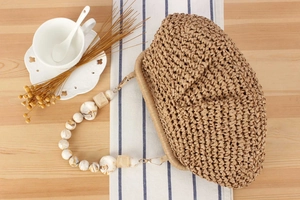 Detailed texture of beige woven straw handbag with unique marble resin bead strap