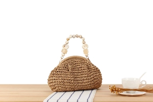Detail of hand-woven straw bag featuring unique resin bead handle and natural texture