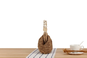 Detail of handwoven straw bag featuring unique marble textured beaded handles for summer