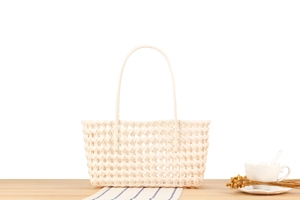 Close-up of cream woven hollow tote bag featuring intricate basket weave and long handles