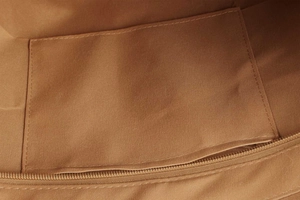 Detailed view of canvas bag interior showing stitching, open pocket and zipper compartment