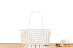 Detail of white woven basket tote bag with handles on a minimalist lifestyle table setting