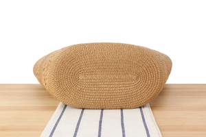Detailed close-up of the reinforced woven base on a khaki straw tote bag