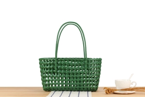 Close-up of green hollow-out woven basket bag on a wooden table for beach vacation
