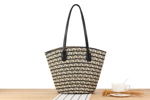 Detail shot of woven tote bag with monochrome monogram pattern on a wooden table