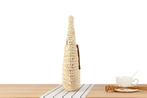 Detailed side view of beige straw bag with brown leather tassel on wooden table