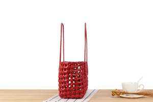 Detail shot of a red woven basket bag with a stylish hollow geometric pattern on wood