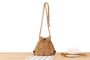 Detail of hand-woven khaki crochet bucket bag showing hollow texture and wooden beads