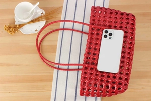 Detailed weave of red hollow basket bag with matching handles beside a smartphone