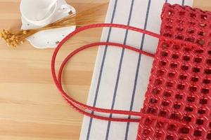 Top view of red woven hollow basket bag with matching handles on a rustic wooden table