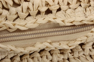 Macro detail of natural straw woven bag with matching zipper closure and textured fibers