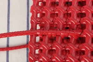 Detail of red hollow woven basket bag showing intricate mesh texture and craftsmanship