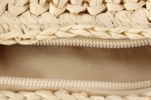 Detail of sturdy zipper closure and inner fabric lining on the woven straw beach bag