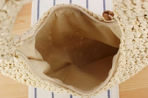 Detail of ivory woven straw bag with zipper closure and smooth beige fabric lining