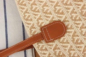 Detail of hand-woven straw bag texture with premium brown leather strap and white stitching
