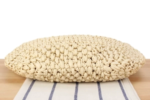 Detail view of woven straw clutch bag showing textured craftsmanship on wooden surface