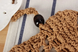Detail of handmade cotton rope weave with a polished wooden bead and rustic drawstring cord