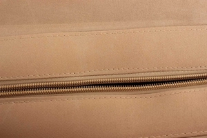 Close-up of the smooth zipper and fine stitching on a khaki woven shoulder bag