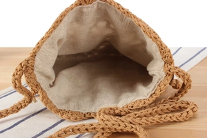 Detail view of woven straw bucket bag showing natural cotton lining and inner texture