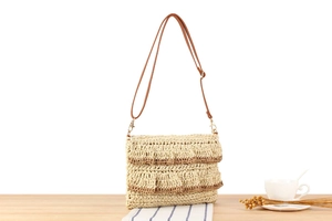 Detail of bohemian straw bag with brown lace layers and adjustable leather strap