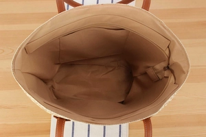 Detail view of woven tote bag featuring khaki fabric lining and internal zipper pocket