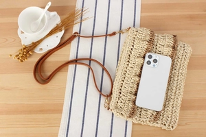 Detail of hand-woven straw bag with faux leather strap and interior space for smartphone