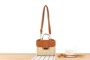 Macro shot of summer woven crossbody bag with brown leather flap and golden hardware