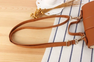 Detail of adjustable caramel PU leather shoulder strap with gold metal buckles on woven bag
