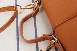 Close-up of brown leather woven bag with gold metal lobster clasp and D-ring hardware