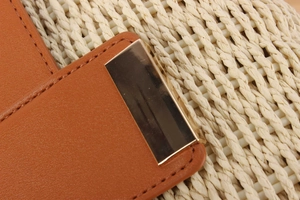 Close-up of brown leather bag featuring a polished gold rectangular buckle and fine stitching