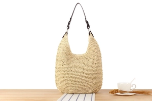 Close-up of the hand-woven texture and brown leather strap of the straw hobo bag