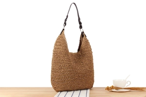 Detailed texture of dark brown hand-woven straw bag with premium leather handle and metal ring