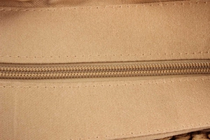 Detailed close-up of smooth zipper closure and neat stitching on woven canvas bag