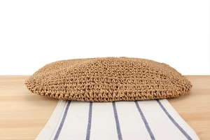 Detailed view of hand-woven straw bag texture on a rustic light wooden surface