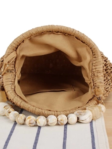 Fashionable woven bucket bag with acrylic bead handle on a casual beach aesthetic background