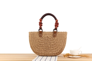 Detail view of handmade straw handbag with wooden beads and brown fabric handles